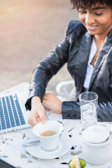Latin businesswoman drinking coffee. Smiling businesswoman networking wiht tablet and cellphone