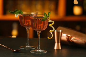 Glasses of tasty cosmopolitan cocktail, spoon and shaker on table in bar