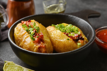Frying pan with baked potato on dark background