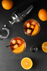 Composition with tasty aperol spritz cocktail and fresh oranges on dark background