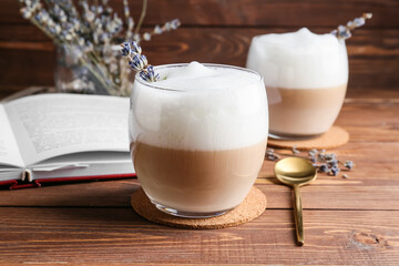 Glasses of tasty lavender latte and book on wooden background