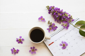 Obraz na płótnie Canvas hot coffee espresso, calendar with purple flowers arrangement flat lay postcard style on background white wooden
