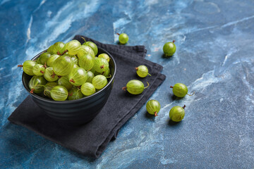 Bowl with fresh ripe gooseberry on color background