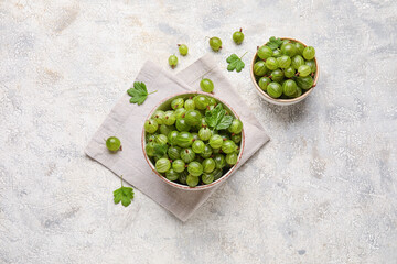 Bowls with fresh ripe gooseberry on grunge background
