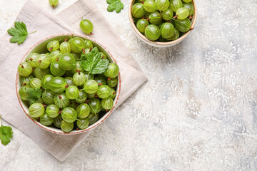 Bowls with fresh ripe gooseberry on grunge background