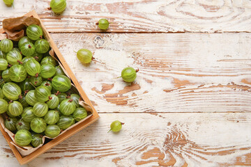 Box with fresh ripe gooseberry on wooden background