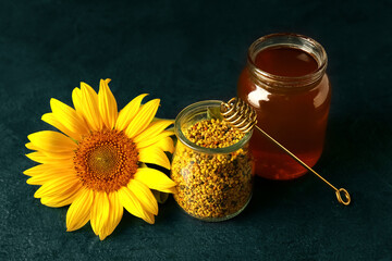 Jars of bee pollen and honey on dark background