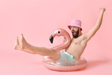 Emotional young man with inflatable ring on color background