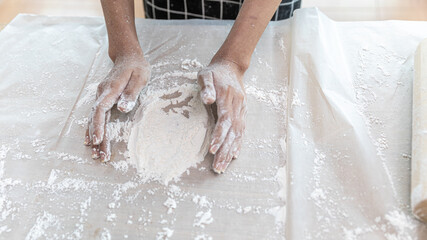 Hands of a young lady working with bakery flour and mixing other ingredients on the table. Girl enjoys preparing materials for making bakery products
