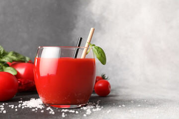 Glass of tasty tomato juice on grey background