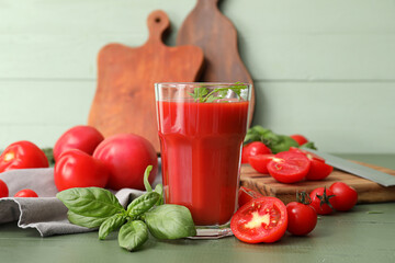 Glass of tasty tomato juice on color wooden background