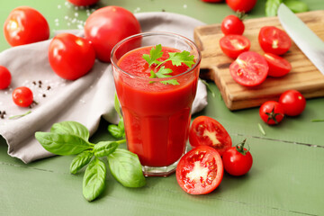 Glass of tasty tomato juice on color wooden background
