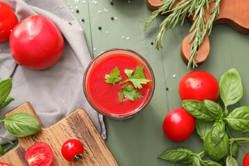 Glass of tasty tomato juice on color wooden background
