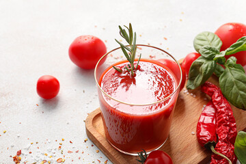 Glass of tasty tomato juice on light background