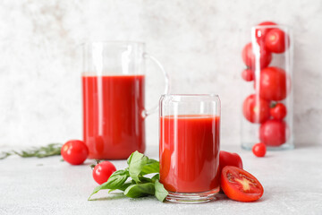 Glass of tasty tomato juice on light background