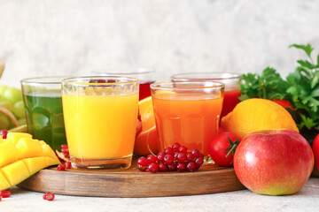 Glasses with healthy juice, fruits and vegetables on light background