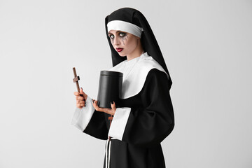 Woman dressed for Halloween as nun with mortuary urn on light background