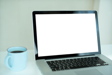 Isolated with clipping path on empty blank screen of laptop. Laptop computer on the table and a cup of coffee.