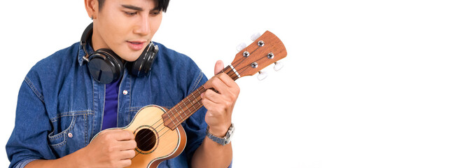 Young asian man with headphones playing an Ukulele guitar. Portrait on white background with studio light. Close Up