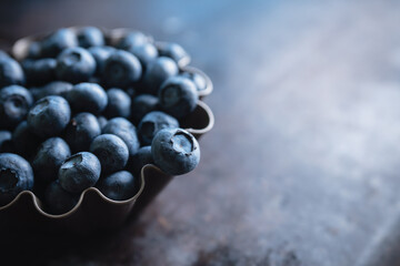 Blueberries in small baking dish ready for making cupcakes on rustic background. Selective focus. Shallow depth of field. © maxandrew