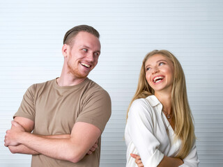 Fototapeta premium Young caucasian couple stand with arms folded, made eye contact, and smile at each other.