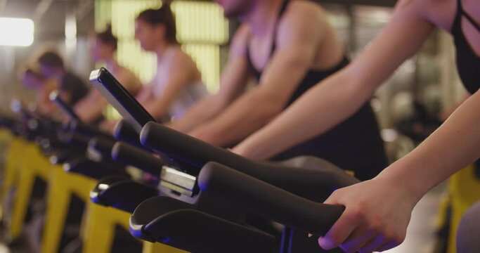 Group of athletic young people stationary bicycle doing spinning at gym . A group of young women and men train on sports training equipment in a fitness gym . Healthy Lifestyle and Sport Concepts