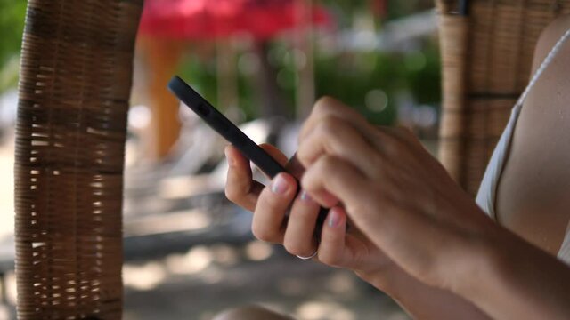 Close up of female hands using smartphone while relaxing on a beach 