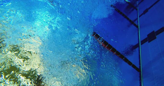 Under water view of professional female swimmer . Underwater footage of woman jumping into water . Swimmer jumping in big swimming Woman swimmer dive in water pool . Slow Motion .