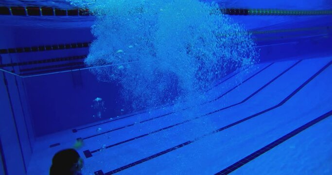 Under water view of professional female swimmer . Underwater footage of woman jumping into water . Swimmer jumping in big swimming Woman swimmer dive in water pool . Slow Motion .