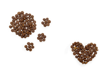 Dry food for dogs and cats in the shape of a heart and in the shape of a footprint isolated on white background. Food for cats and dogs. Healthy pet food concept.