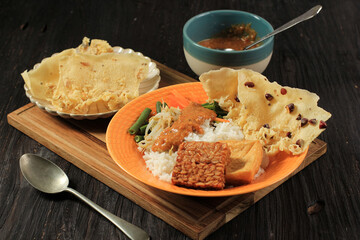 Nasi Pecel. Traditional Javanese Rice Dish of Steamed Rice with Vegetable Salad, Peanut Sauce Dressing, Tempeh, Tofu Beancurd, and Peyek Crackers. Pecel Madiun is Most Popular Variant