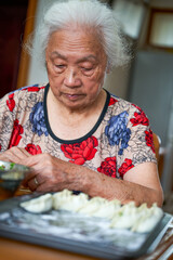 An old grandmother in a Chinese family is making dumplings