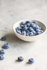Freshly picked blueberries in a  bowl. Juicy and fresh berries with green leaves on a rustic table.  Healthy food and nutrition concept