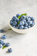 Freshly picked blueberries in a  bowl. Juicy and fresh berries with green leaves on a rustic table.  Healthy food and nutrition concept