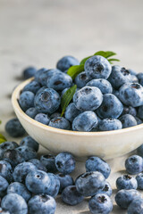 Freshly picked blueberries in a  bowl. Juicy and fresh berries with green leaves on a rustic table.  Healthy food and nutrition concept