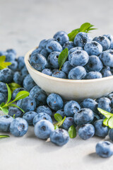 Freshly picked blueberries in a  bowl. Juicy and fresh berries with green leaves on a rustic table.  Healthy food and nutrition concept