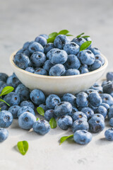 Freshly picked blueberries in a  bowl. Juicy and fresh berries with green leaves on a rustic table.  Healthy food and nutrition concept