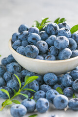 Freshly picked blueberries in a  bowl. Juicy and fresh berries with green leaves on a rustic table.  Healthy food and nutrition concept