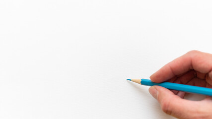 Hand holding wooden blue sharp simple pencil for drawing or sketching on white blank sheet background, close up, copy space. Back to school concept.