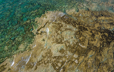 Aerial drone view of sea transparent water with rocks on the bottom. Ocean background