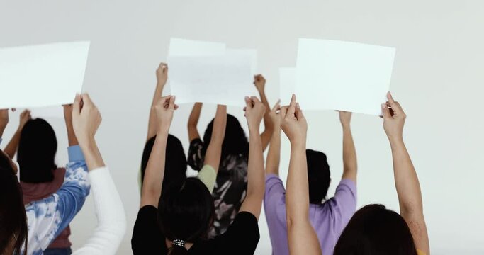 Group of mix age Asian women holding papers banner during participants in protest for something in front of building taken from back view.