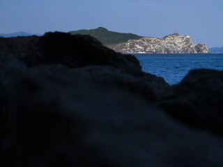 Rocky shore with island on the horizon.