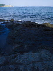 Rocky shore with island on the horizon.