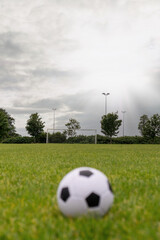 Ball on green grass, Soccer of football goal post in the background.