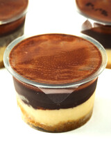 Plastic tub with tasty cream and chocolate dessert on white background