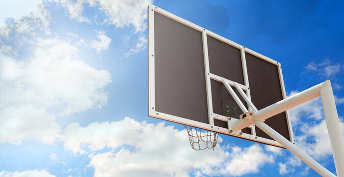Basketball backboard with a basket made of iron chains, close-up against the blue sky. Copy space. Low angle view - Powered by Adobe