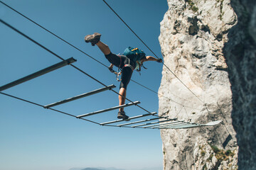 Climber posing on via ferrata  suspended wire bridge