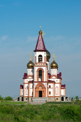Fototapeta na wymiar Church with golden domes against a blue sky with white clouds.