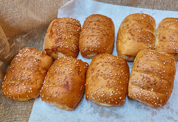 Pan blanco horneado con ajonjoli llamado rollitos de jamón y queso.