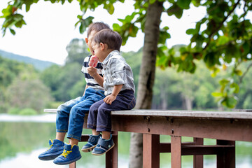 Two brothers share ice cream together at a park by the lake.